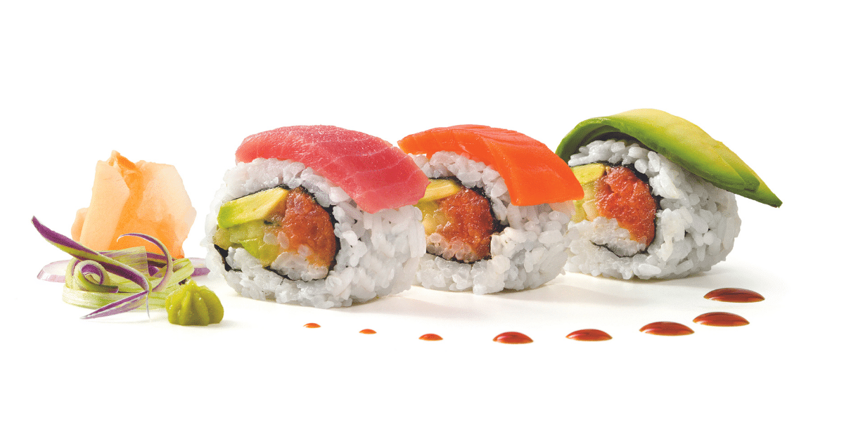 Three pieces of sushi filled with fish, rice and avocado on white background with decorative ginger