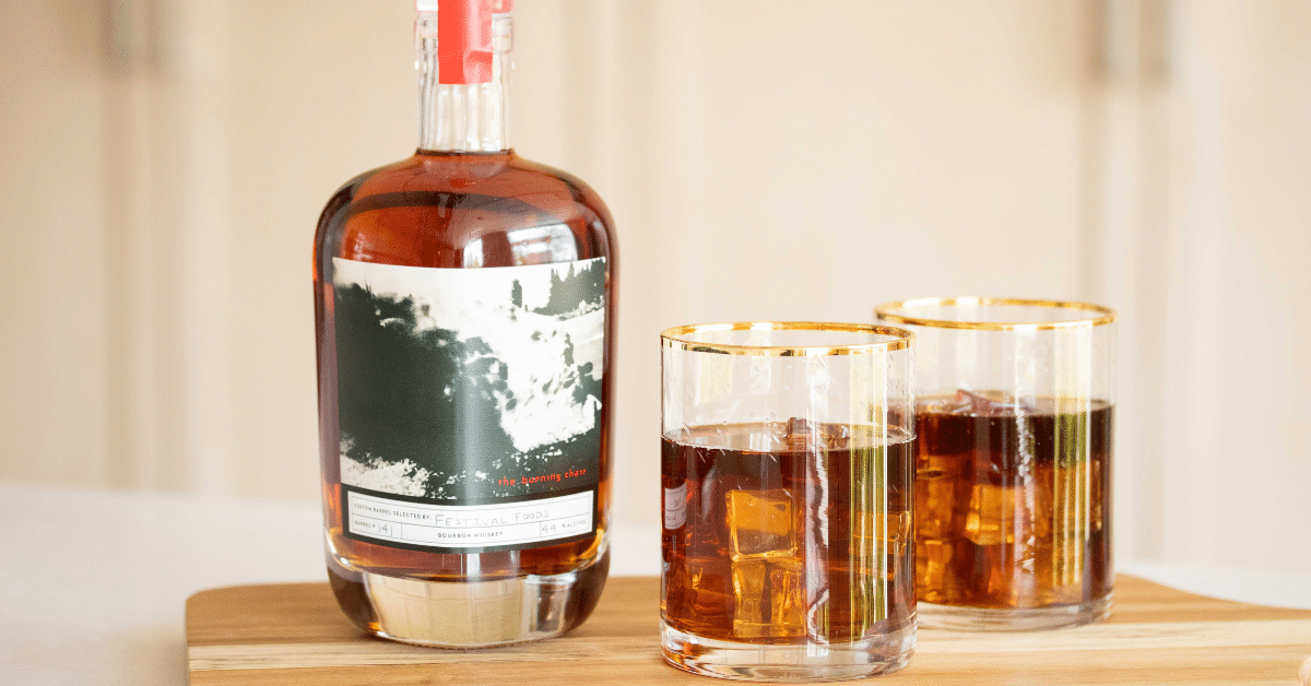 A bottle of bourbon next to two glasses with bourbon