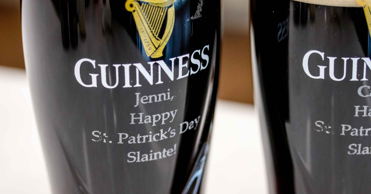 Close-up image of two Guinness glasses engraved with "Happy St. Patrick's Day. Slainte!"