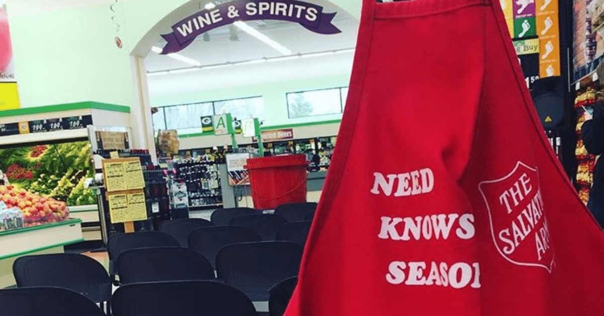 Red Salvation Army apron in foreground with grocery store and red kettle in background