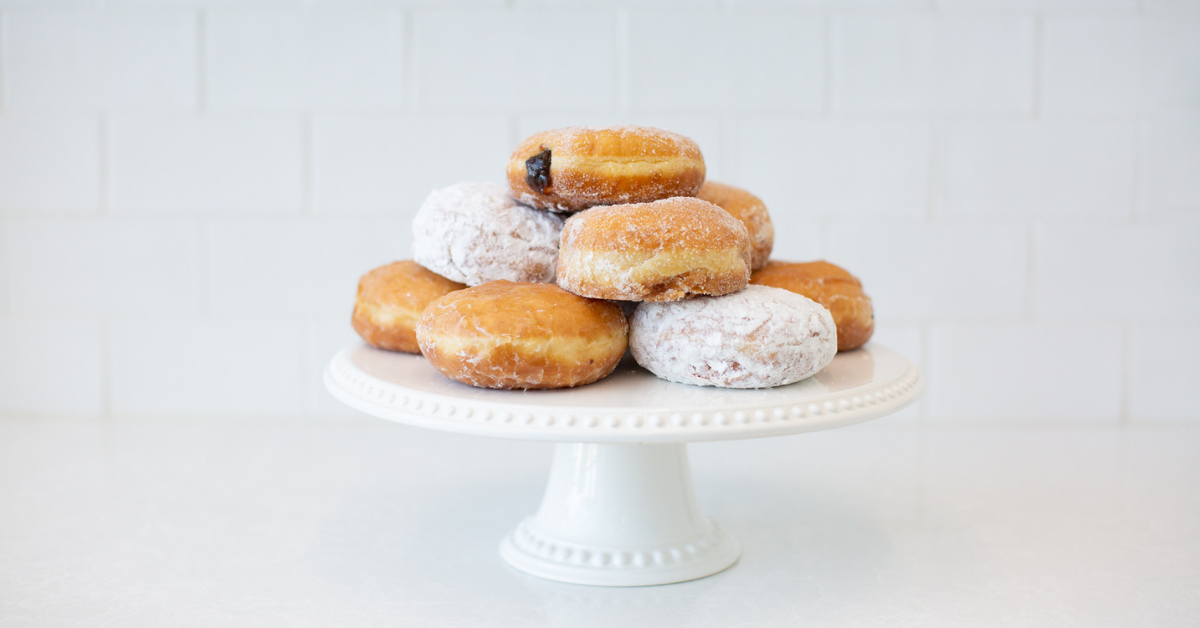 White cake stand with various paczkis piled on top