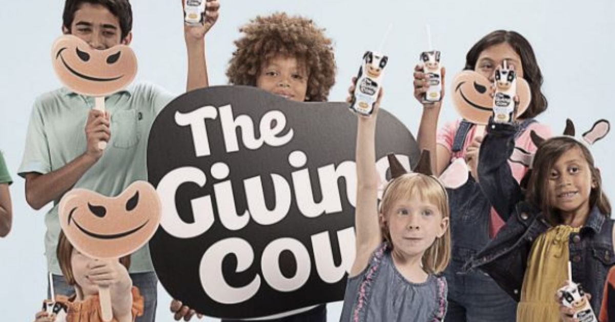 Siz children raise milk cartons by a sign that says "The Giving Cow"