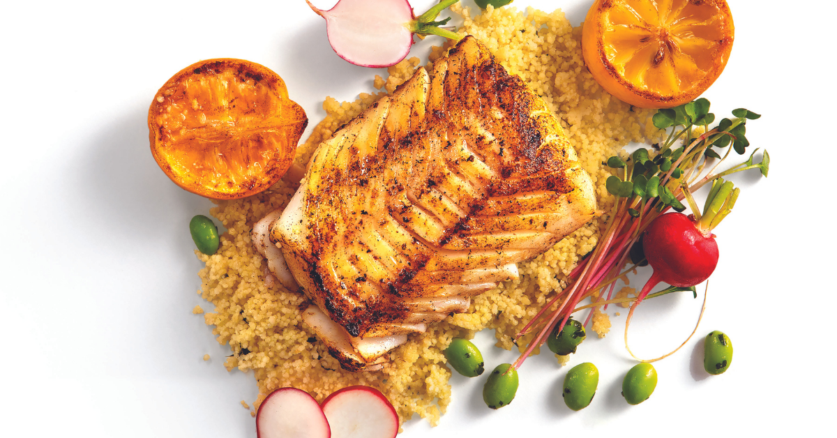 Grilled white fish fillet on bed of grains with halved radishes and herbs scattered around