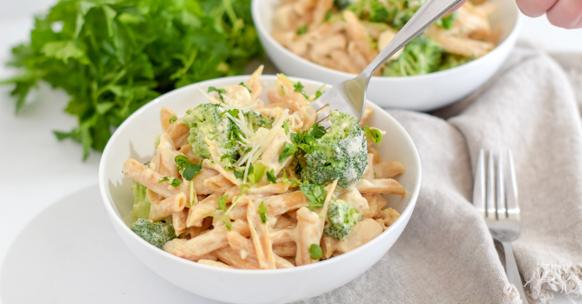 Creamy pasta with broccoli in white bowl with fork taking some out