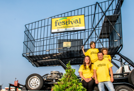 Family standing in front of the Festival Foods big grocery cart