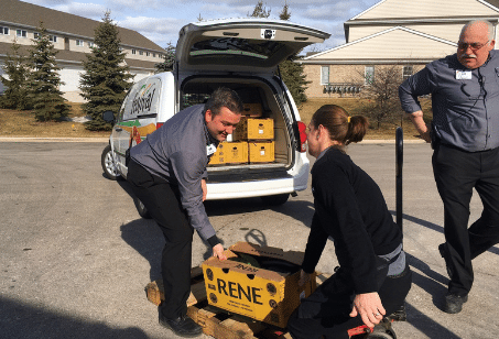 Two people putting products in the back of a van